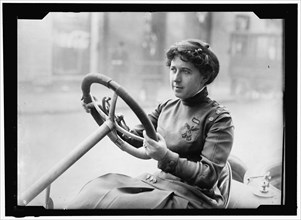 Race car driver Joan Newton Cuneo, seated in racing car, facing left, between 1910 and 1917.