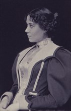 Young woman wearing high collared blouse and mutton-sleeved jacket, facing left, half-length portrait, c1900.