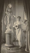 Miss Apperson playing banjo beside statue of "Flora" in niche of Sen. George Hearst's residence, Washington, D.C., 1895.