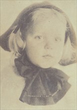Young girl with a hat tied with a large bow, head-and-shoulders portrait, facing front, c1900.