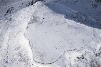 Ingleborough Iron Age univallate hillfort and associated hut circle earthworks in the snow, North Yorkshire, 2018.