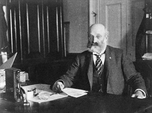 Col. William H. Crook, a White House employee, half-length portrait, seated at desk, facing left, between 1890 and 1910.