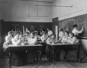 Group of young women performing atmospheric pressure experiments while studying..., (1899?). Creator: Frances Benjamin Johnston.