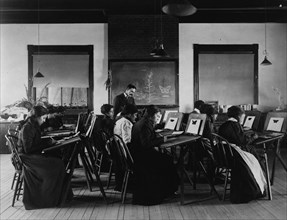 Group portrait of teacher and students at Hampton Institute painting watercolor pictures of butterflies, 1899 or 1900.