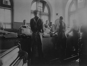 Workers wetting sheets prior to printing paper money at the Bureau of Engraving & Printing, c1895.