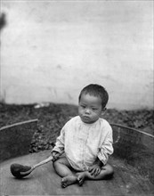 Asian(?) baby seated holding spoon or ladle, World's Columbian Exposition, Chicago, Illinois, 1891 or 1892.