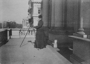Frances Benjamin Johnston with camera on balcony of State, War and Navy Building..., 1888. Creator: Frances Benjamin Johnston.