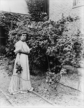 Frances Benjamin Johnston, full-length portrait, standing in her garden..., c1890 - 1910. Creator: Unknown.