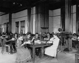 Interior view of library reading room with male and female students... Tuskegee Institute, c1902. Creator: Frances Benjamin Johnston.