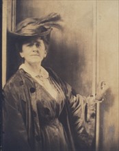 Gertrude Ka¨sebier, wearing feathered hat, standing, facing front, half-length portrait, c1900. Creator: Adolph de Meyer.