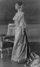 Alice Roosevelt Longworth, full-length portrait, standing next to chair, facing left, 1903. Creator: Frances Benjamin Johnston.