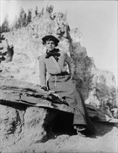 Frances Benjamin Johnston, full-length portrait, seated on rock in Yellowstone National Park, 1903. Creator: Frances Benjamin Johnston.