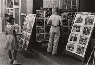 Children looking at posters in front of movie, Saturday, Steele, Missouri,  1938-08.