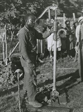 An African American man fixing a well's tube into the ground near Ridge, Maryland, July 1941.