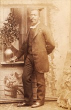 Full-length portrait of man, with studio props, c1880-c1889. Creator: Richmond Photograph Co.