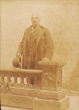 Studio portrait of man dressed in suit and coat, holding bowler hat, c1890. Creator: Steinhardt.