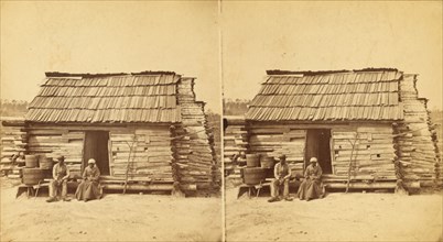 Uncle Ben's cabin, [Elderly couple sitting in front of a cabin], (1868-1900?). Creator: Unknown.