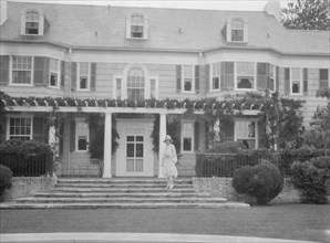 Gossler, Philip, Mrs., standing in front of residence, between 1927 and 1929. Creator: Arnold Genthe.