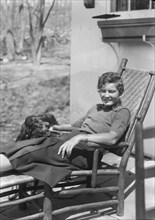DeLamar, Alice, Miss, with dog, seated outdoors, between 1927 and 1942. Creator: Arnold Genthe.
