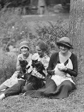 Egger, Gabrielle, Miss, and friends, with cats, seated outdoors, between 1926 and 1930. Creator: Arnold Genthe.