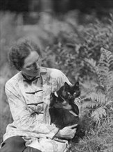 Egger, Gabrielle, Miss, friend of, with cat, seated outdoors, between 1926 and 1930. Creator: Arnold Genthe.