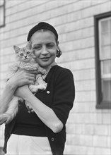 Leonard, Mrs., with cat, standing outdoors, between 1926 and 1938. Creator: Arnold Genthe.