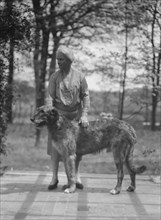 Noland, Charlotte, Miss, with dog, standing outdoors, 1931 May 8. Creator: Arnold Genthe.
