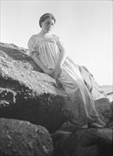 Wilson, Helen, Mrs., seated on rocks at the beach, between 1906 and 1928. Creator: Arnold Genthe.