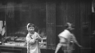 Young girl walking down the street, looking into the camera, Chinatown, San Francisco, c1896-1906. Creator: Arnold Genthe.