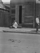 Woman sitting on steps holding a basket, New Orleans, between 1920 and 1926. Creator: Arnold Genthe.