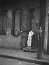 Woman standing in a doorway in the French Quarter, New Orleans, between 1920 and 1926. Creator: Arnold Genthe.