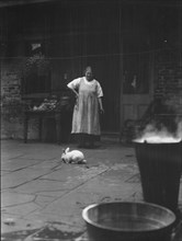 Woman and rabbit in a courtyard, New Orleans, between 1920 and 1926. Creator: Arnold Genthe.