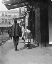 Man and a young girl walking down a sidewalk, Chinatown, San Francisco, between 1896 and 1906. Creator: Arnold Genthe.