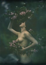 Nude woman wearing floral garlands or wreaths, between 1906 and 1942. Creator: Arnold Genthe.