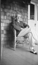 Arnold Genthe seated in a chair on a porch, between 1911 and 1942. Creator: Arnold Genthe.