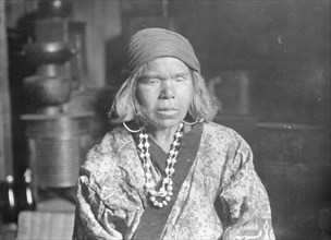 Ainu woman wearing a headscarf, earrings, and a necklace, 1908. Creator: Arnold Genthe.