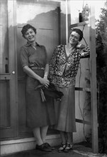 Mrs. Mary Benson and Alice DeLamar, standing by the door of a house, 1933. Creator: Arnold Genthe.