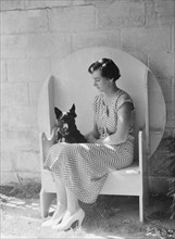 Mrs. Walter Fletcher with dog, seated outdoors, between 1933 and 1942. Creator: Arnold Genthe.