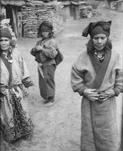 Three Ainu women outside in the village lane, 1908. Creator: Arnold Genthe.