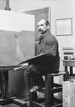 Unidentified man, seated at his easel, portrait photograph, between 1896 and 1942. Creator: Arnold Genthe.
