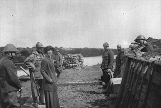 'La Reine des Belges sur les lignes de L'Yser; Un soldat (a droite) joue un air de violon', 1916. Creator: Unknown.