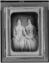 Two unidentified women, three-quarter length portraits, seated, between 1851 and 1860. Creator: H. R. Marks.