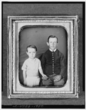 Unidentified boy seated in chair with child standing to left, three-quarter..., between 1850 & 1860. Creator: Unknown.