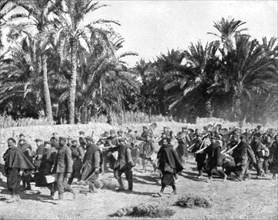 'Tandis que.; Voici des prisonniers allemands traversant une riante oasis algerienne pour..., 1917 Creator: Unknown.