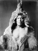Bear's Belly, Arikara Indian half-length portrait, facing front, wearing bearskin, c1908. Creator: Edward Sheriff Curtis.