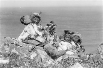 Four Eskimo children, at edge of cliff, in holiday costume, Nunivak, Alaska, c1929. Creator: Edward Sheriff Curtis.