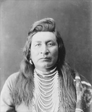 Nez Percé man, head-and-shoulders portrait, facing front, wearing bead necklace..., c1899. Creator: Edward Sheriff Curtis.