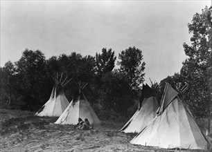 An Assiniboin camp containing four tepees with Indians seated on ground, c1908. Creator: Edward Sheriff Curtis.