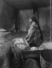 A Skokomish Indian chief's daughter, half-length portrait, seated on canoe, facing left, c1913. Creator: Edward Sheriff Curtis.