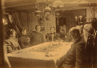 Captains, their wives, and two female tourists sitting around a table aboard ship...,Alaska, (1897?) Creator: Alfred Lee Broadbent.